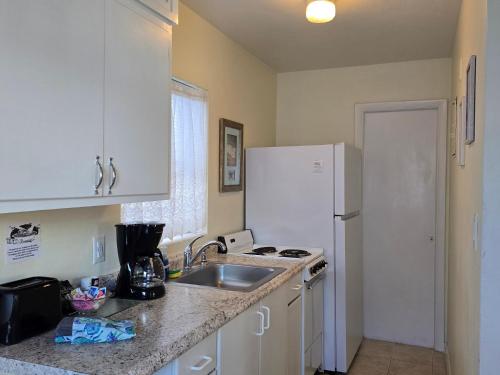 a kitchen with a sink and a white refrigerator at Oceanfront Sea Scape Motel in Melbourne