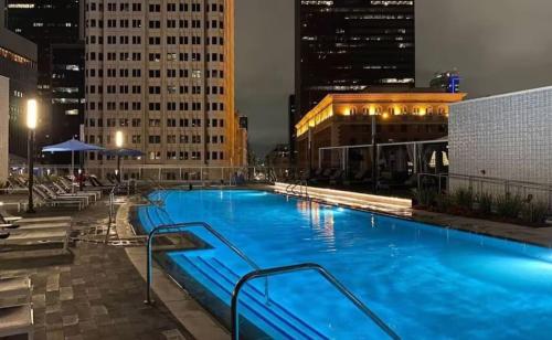 a large swimming pool in a city at night at Stylish 3BR High-Rise with Pool, Hot Tub & Rooftop Views in Los Angeles