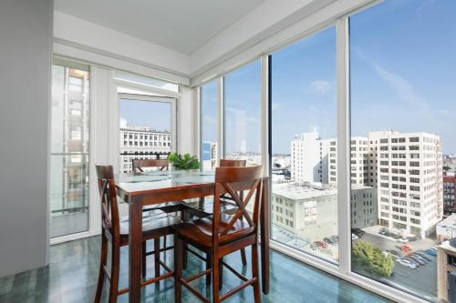 a dining room with a table and chairs and large windows at Stylish 3BR High-Rise with Pool, Hot Tub & Rooftop Views in Los Angeles