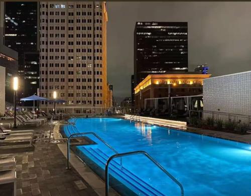 a large swimming pool in a city at night at Stylish 3BR High-Rise with Pool, Hot Tub & Rooftop Views in Los Angeles