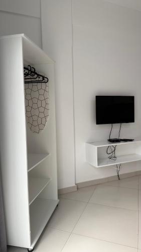 a white room with a television and a white refrigerator at Urban Praia Maria - ApartHotel in Praia
