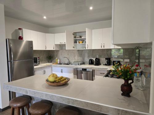 a kitchen with white cabinets and a bowl of fruit on a counter at Villas TEAKAVEHERE - Fare OPUHI in Pirae