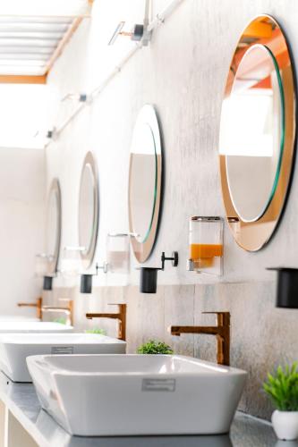 a bathroom with three sinks and two mirrors at Leo Vishroam in Mysore