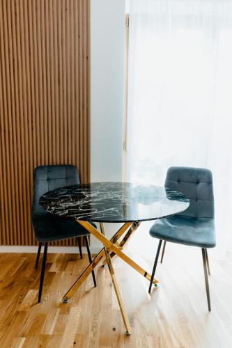 a glass table and two chairs in a room at Evo Residence Taietura Turcului in Cluj-Napoca