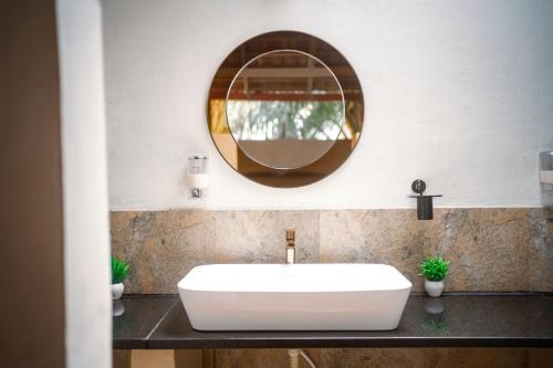 a bathroom with a white sink and a mirror at Leo Vishroam in Mysore