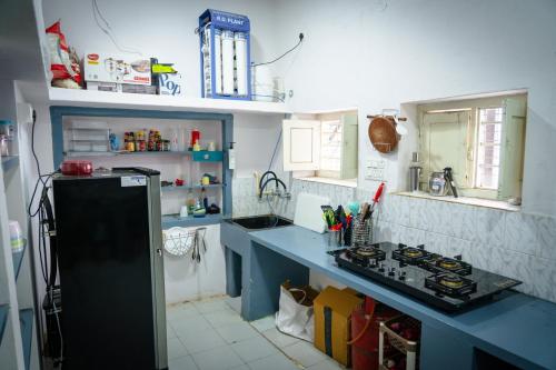 a kitchen with a black refrigerator and a sink at Leo Vishroam in Mysore