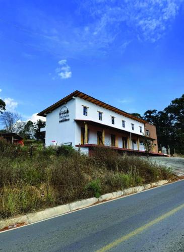 a white building sitting on the side of a road at Hotel Tlalcosahua, hotel de Montaña, Tapalpa in Tapalpa