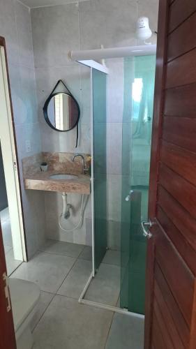 a bathroom with a sink and a mirror and a shower at Pelados Beach Hostel in Pipa