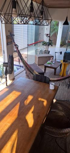 a large wooden table in a room with a pool at Pelados Beach Hostel in Pipa