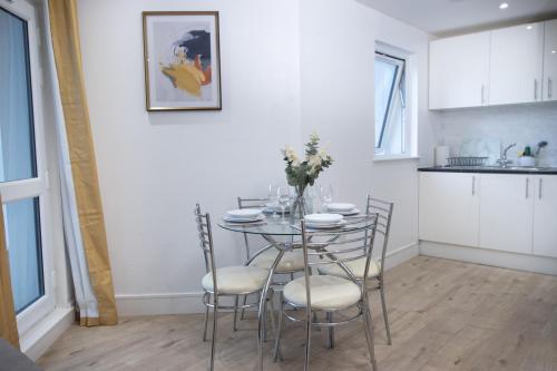a kitchen and dining room with a table and chairs at Midland Apartment I 1-min walk to town centre & station I 8-mins to airport I private balcony in Luton