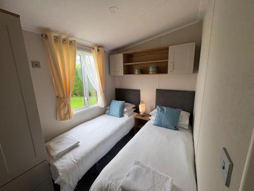 two beds in a small room with a window at Campsie Glen Holiday Park in Glasgow