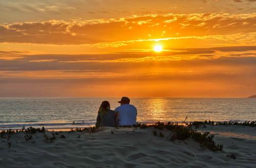 a man and woman sitting on the beach watching the sunset at Pacific Plaza #511 - Oceano Escape - 1BdrmUp-K-QSofa in Oceano