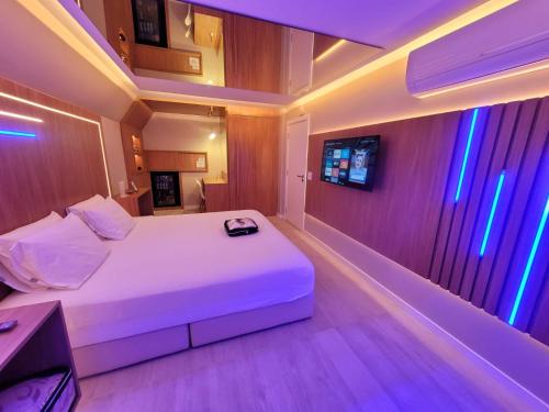 a bedroom with a white bed with purple lights at Astral Motel in Caxias do Sul