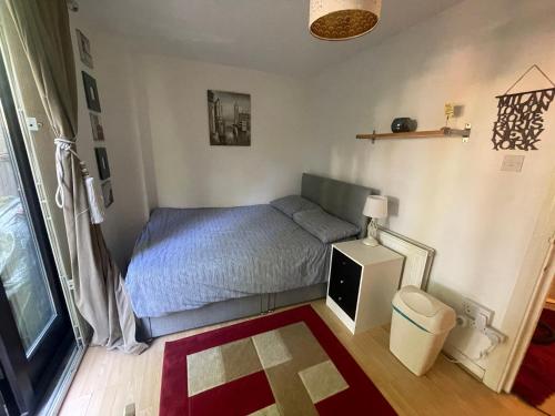 a small bedroom with a bed and a trash can at Charming Bedroom with Garden in London