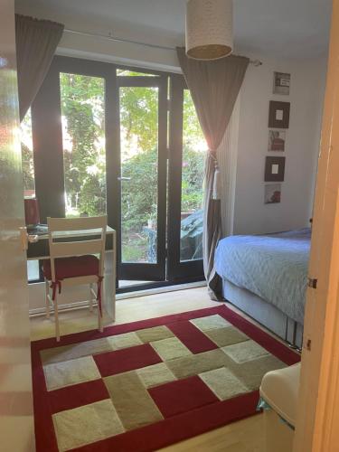 a bedroom with a bed and a desk and a window at Charming Bedroom with Garden in London