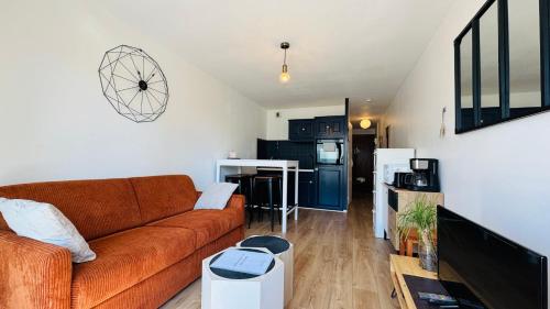 un salon avec un canapé et une cuisine dans l'établissement L’échappée avec vue sur la mer, à Merlimont