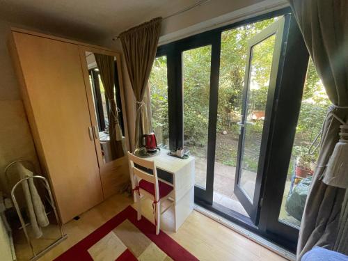 a room with large windows and a table with a mirror at Charming Bedroom with Garden in London