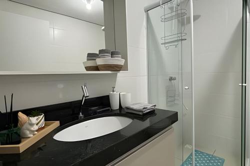 a bathroom with a sink and a glass shower at Apto prático | 2 Qtos + Lazer + Garagem in Perequê