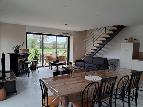 un salon avec une table et des chaises et un escalier dans l'établissement Au calme à la campagne 13 pers, à La Mézière