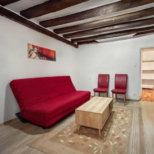 un salon avec un canapé rouge et deux chaises dans l'établissement Appartement Style New York, Centre Ville, à Montargis