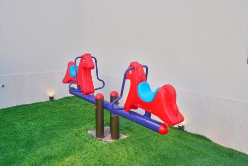 a playground with red and blue chairs on the grass at شاليهات مسرة الياقوت - alyaqout chalet in Jeddah