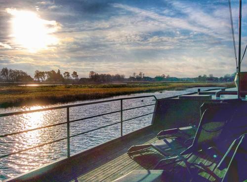 a boat sitting on a river with the sun setting at Urlauberschiff Neptun im Ostseebad Prerow in Prerow