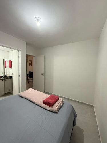 a bedroom with a bed with a red towel on it at Apartamento Parque Trianon in Araçatuba