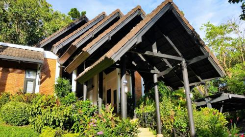 a house with an awning in a garden at Kamala Beach Estate Resort - SHA Extra Plus in Kamala Beach