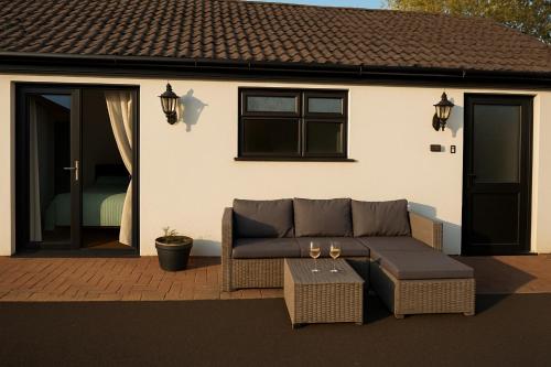 a couch and a table in front of a house at Lytton Tree Lodge Near Southwold in Reydon