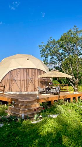 ein Pavillon mit zwei Stühlen und zwei Sonnenschirmen in der Unterkunft Alachiq Glamphouse in İsmayıllı