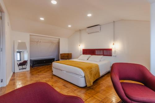 a bedroom with a bed and two red chairs at BABhouse Casa das Abelhas - Coração do Douro in São João da Pesqueira