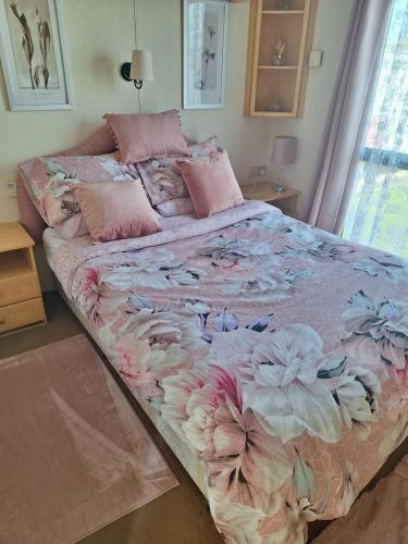 a large bed with pink and white flowers on it at Highfield and the Haven Caravan Skegness in Lincolnshire