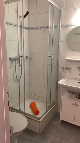 a bathroom with a shower with an orange towel at Haus Atlantic Leukerbad in Leukerbad