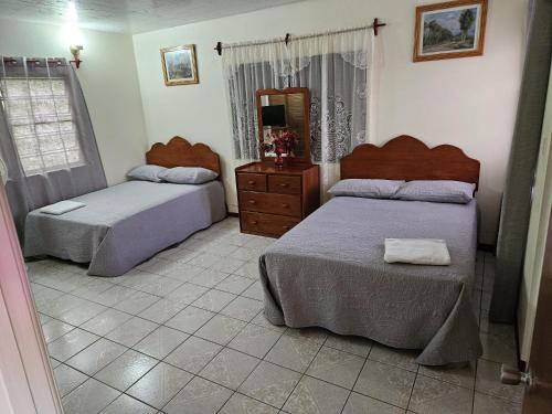 a bedroom with two beds and a dresser and a mirror at Paradise Villa Rooms in Plymouth