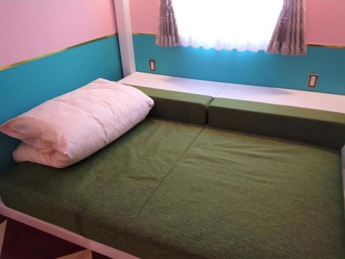 un letto in una piccola stanza con un cuscino rosa di FourStoriesHotelMaihama Tokyo Bay - Vacation STAY 73130v a Tokyo