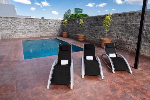 two chairs and a swimming pool on a patio at Garden Park Hotel in San Luis Potosí
