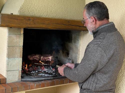 a man is cooking food in a brick fireplace at Maison de Vacances MACOU 2 in Capdrot