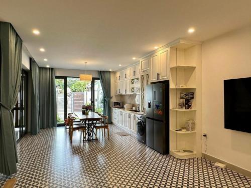 a kitchen with white cabinets and a table and a television at GG Garden Home in Bao Loc