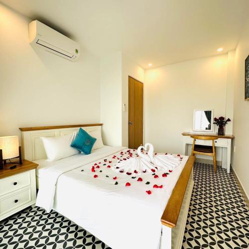 a bedroom with a white bed with red roses on it at GG Garden Home in Bao Loc