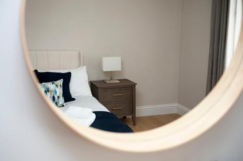 a mirror of a bedroom with a bed and a nightstand at Fresh and spacious 3 bedroom home in Angus