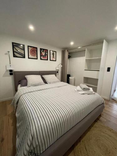 - une chambre avec un grand lit et des draps rayés dans l'établissement Appartement neuf 1 Chambre en rez de jardin avec, à Lovagny
