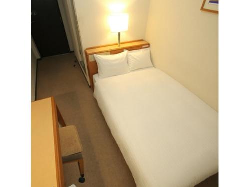 un lit dans une chambre avec une lumière dessus dans l'établissement Smile Hotel Fukuoka Okawa - Vacation STAY 81529v, à Ōkawa