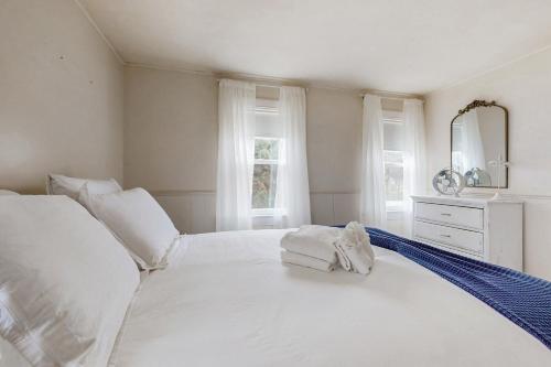 a white bedroom with a bed with towels on it at Namskaket Retreat in Orleans