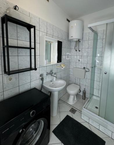 a bathroom with a toilet sink and a washing machine at Apartment Moris in Vodnjan