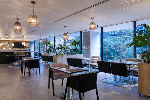 a restaurant with tables and chairs and large windows at Novotel Bogota Parque 93 in Bogotá