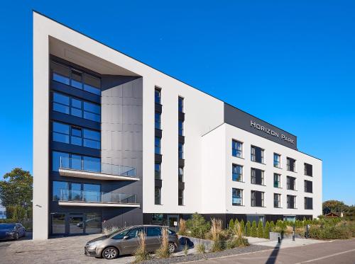 a building with a car parked in front of it at Boszkowo Horizon Park Apartament 14 "Laguna" in Boszkowo