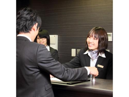 a woman shaking hands with a man at a desk at Hotel AreaOne Chitose - Vacation STAY 99100v in Chitose