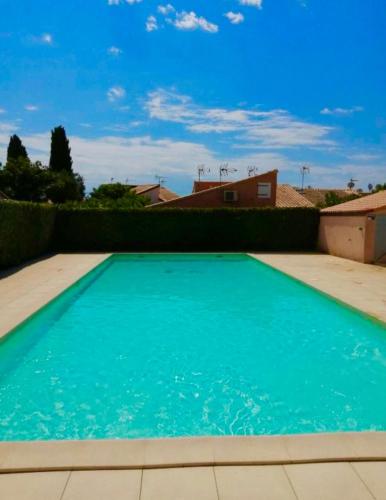 une grande piscine bleue devant une maison dans l'établissement Pavillon avec jardin et piscine saisonnière, à Gruissan