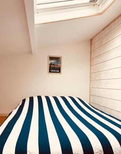 - une chambre avec un lit rayé bleu et blanc dans l'établissement Pavillon avec jardin et piscine saisonnière, à Gruissan