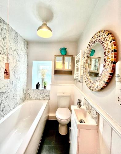 a bathroom with a tub and a toilet and a sink at Wicket Green Cottage Hayfield in Hayfield